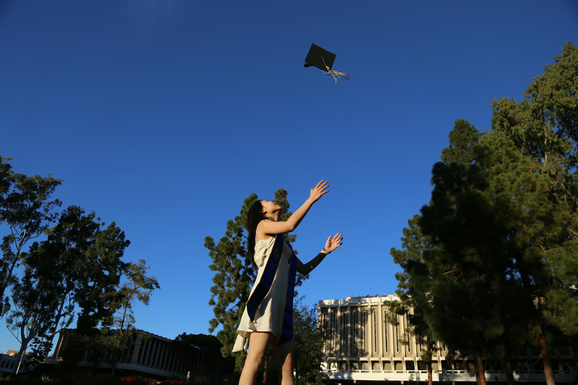 A proud graduate throwing their cap in the air surrounded by family and friends celebrating.