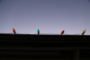 A worker installing colorful Christmas lights on a home.