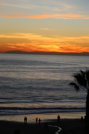 A vibrant sunset over a tropical beach with travelers enjoying the view.