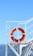 A bright orange life preserver is mounted on the white railing of a boat deck. The background features a clear blue sky with mountains visible in the distance. The life preserver is marked with the text 'Victoria Andina 1175'.