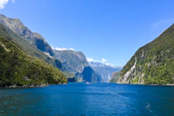 The iconic Segla mountain rising sharply above a calm fjord under a clear blue sky.
