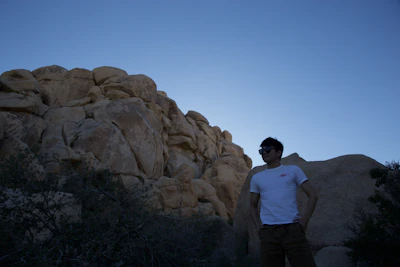 Model wearing stone white rugged vest against a backdrop of rocky terrain at dawn.