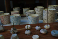 Several cups displayed on a shelf with beads and spiritual artifacts in the background.