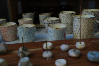 Colorful keychains and ceramic cups displayed together on a cozy fabric background.