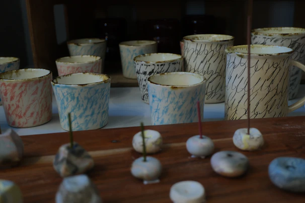 Colorful keychains and ceramic cups displayed together on a cozy fabric background.