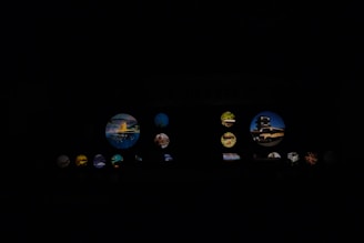 Various circular images illuminated against a dark background. The images contain scenes of landscapes, architecture, and possibly nature elements. Some circles are larger and more prominent, displaying distinct elements like buildings or vibrant natural landscapes.