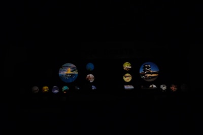 Various circular images illuminated against a dark background. The images contain scenes of landscapes, architecture, and possibly nature elements. Some circles are larger and more prominent, displaying distinct elements like buildings or vibrant natural landscapes.