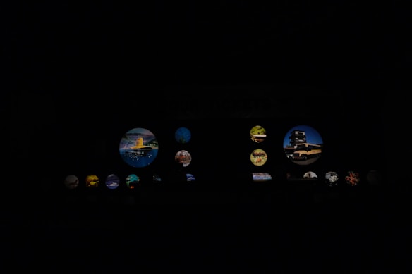 Various circular images illuminated against a dark background. The images contain scenes of landscapes, architecture, and possibly nature elements. Some circles are larger and more prominent, displaying distinct elements like buildings or vibrant natural landscapes.