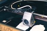 A close-up of a 3D printer with the brand name Creality printed on it. The printer is in the middle of printing with a partially printed object visible on the print bed. The machine has several cables and a metal frame visible.