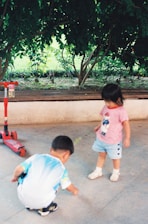 Kids happily playing outside in a small garden area with flowers and toys.