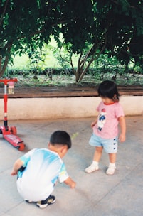 Kids happily playing outside in a small garden area with flowers and toys.