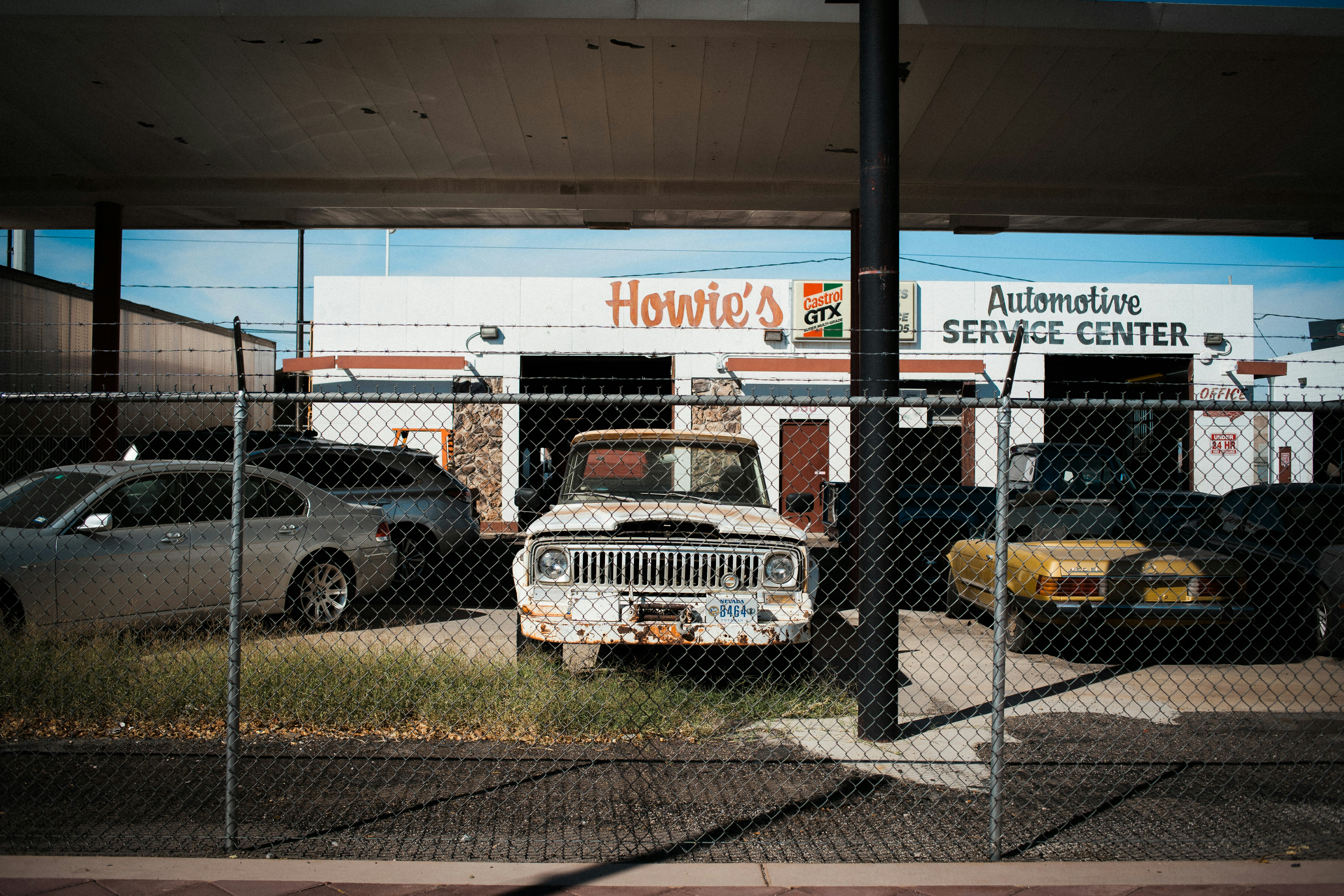 an old truck is parked behind a chain link fence