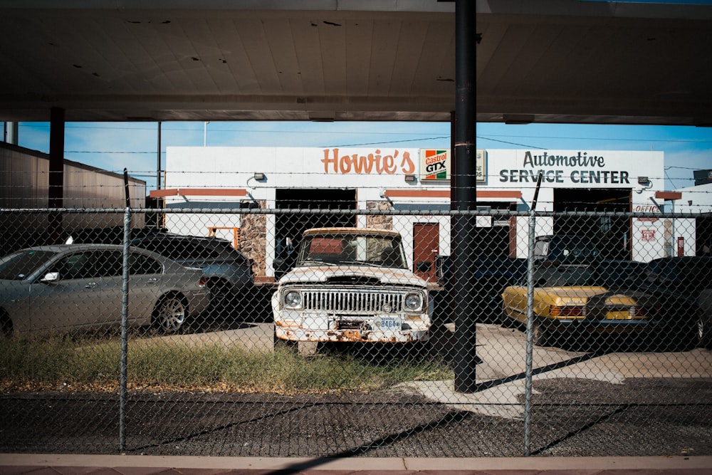 an old truck is parked behind a chain link fence