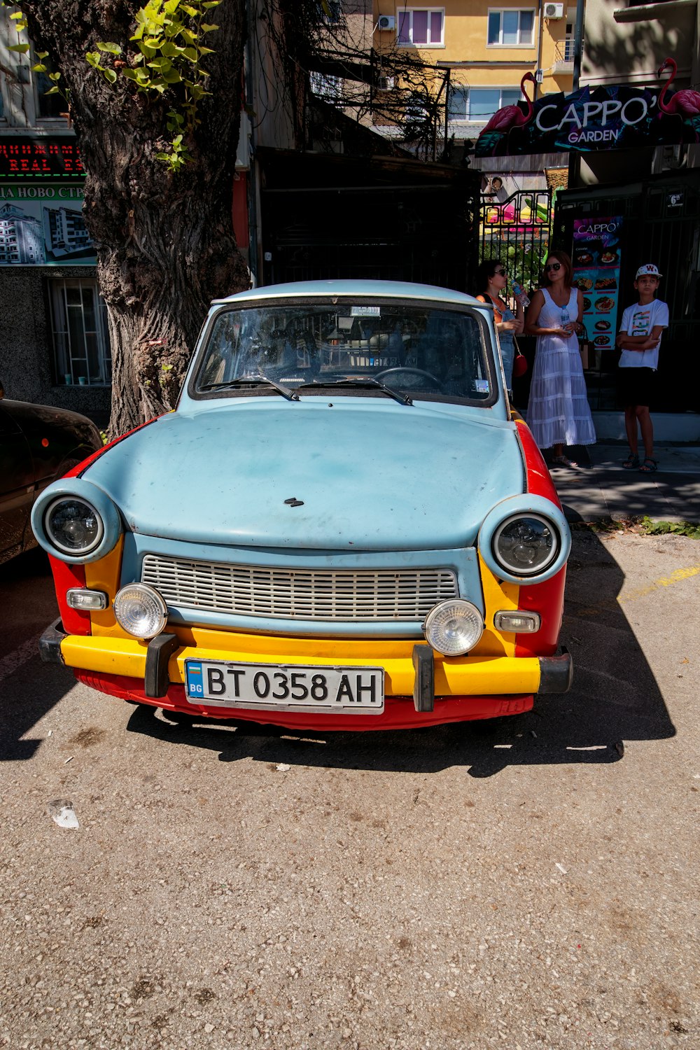 a blue and yellow car parked on the side of the road