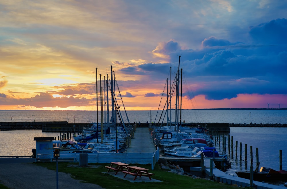 Un muelle con muchos barcos atracados al atardecer