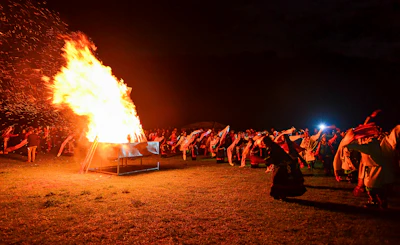 A joyful group of women around a bonfire at night, proudly displaying their patch-covered sashes.
