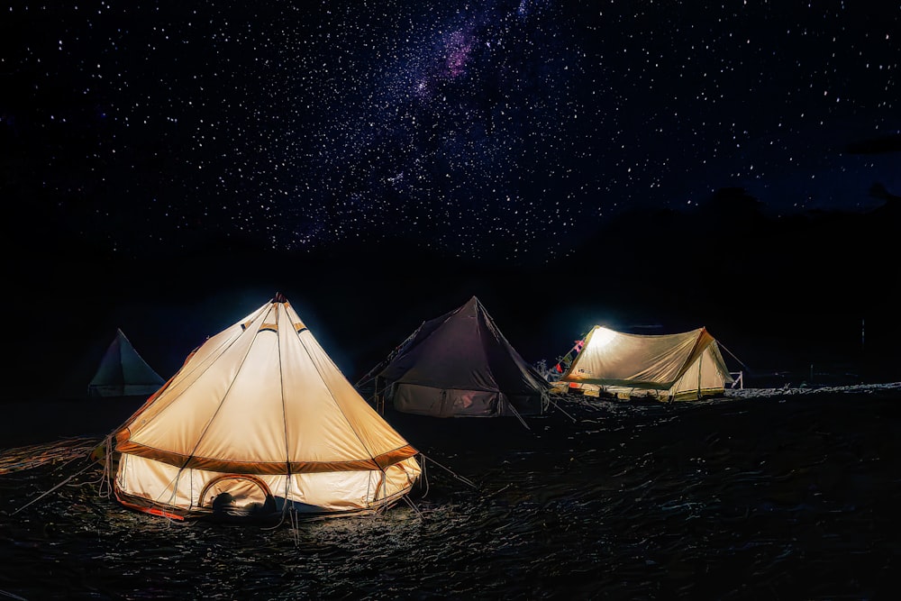 a group of tents sitting on top of a field under a night sky