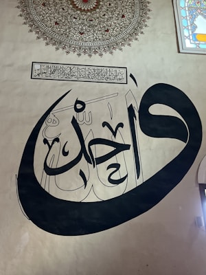 A close-up of a beautifully designed Arabic calligraphy artwork on a wall.