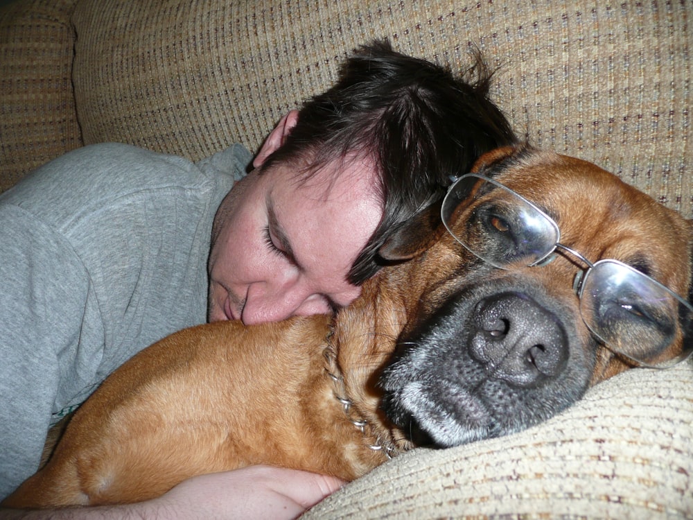 a man laying on a couch next to a dog