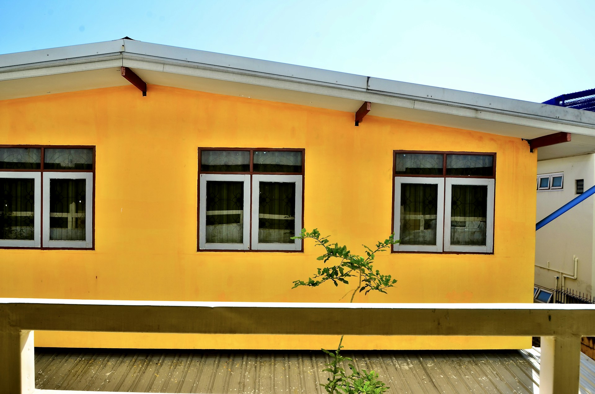 a yellow house with three windows and a wooden deck