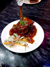 A rustic wooden table displaying a steaming plate of slow-cooked lamb tandır with fresh herbs around.