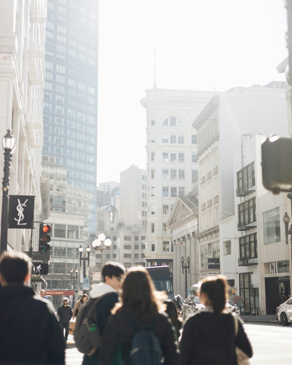 a group of people walking down a street next to tall buildings