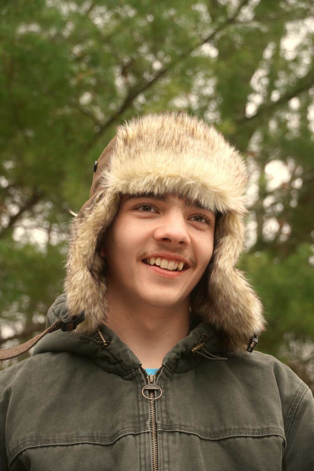 a young man wearing a jacket and a fur hat