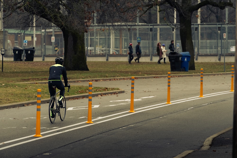 a man riding a bike down a street next to a park