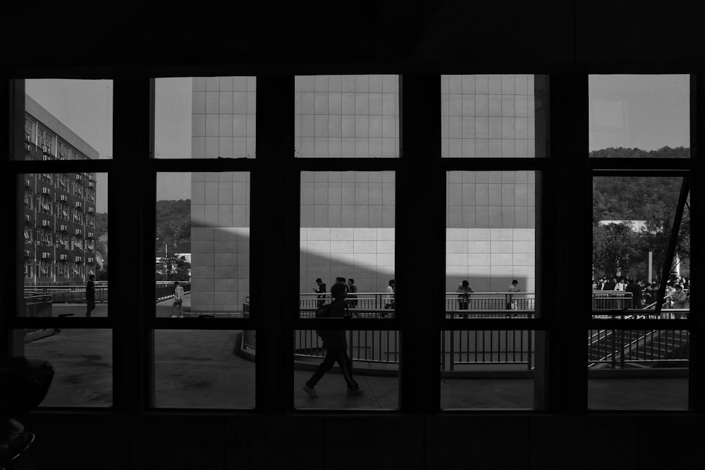 a black and white photo of people walking by a building