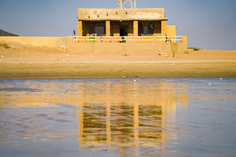 a small building sitting on top of a beach next to a body of water