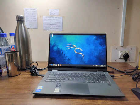 Blueprints and laptops on a desk with a power station visible through the window.