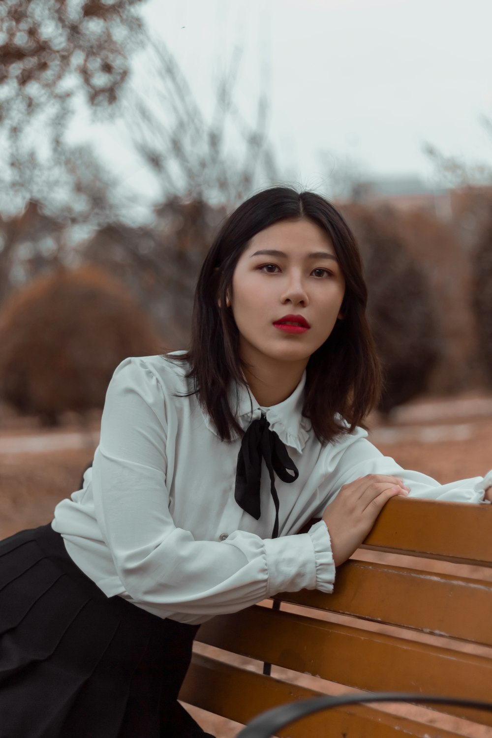 a woman sitting on a wooden bench in a park