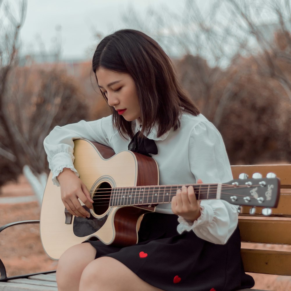 a woman sitting on a bench playing a guitar
