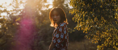 A radiant outdoor portrait of a woman bathed in golden hour light, surrounded by lush greenery.
