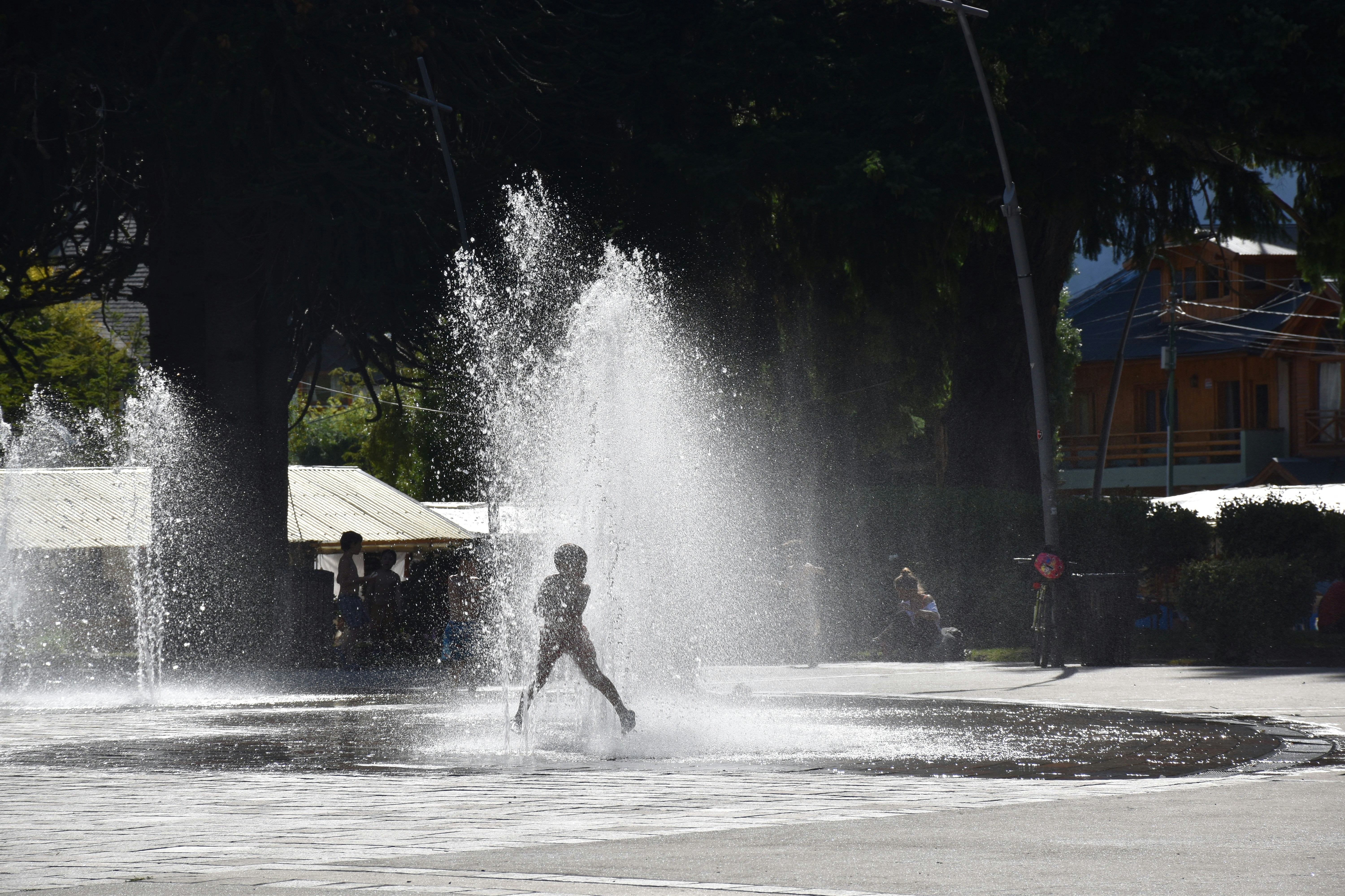 a woman is playing in a fountain in a park