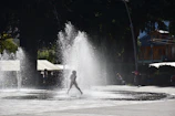A child playing joyfully in a gentle waterfall cascade.