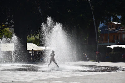 A child playing joyfully in a gentle waterfall cascade.