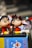 Two cartoon character figurines with large eyes and cheerful expressions are sitting on display, surrounded by various colorful toys and objects. One of the figurines is depicted on a blue box with Japanese text, featuring the character from the Doraemon series.