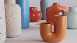 A collection of small ceramic vases in warm reds and oranges arranged on a windowsill.