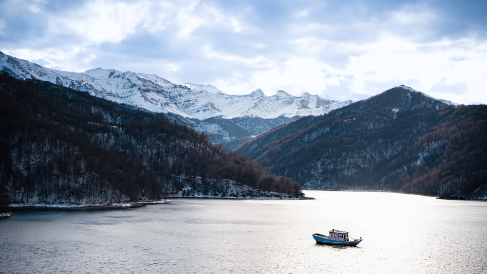 a boat floating on top of a lake surrounded by mountains