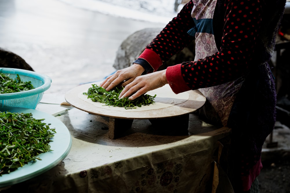 a woman is cutting greens on a plate