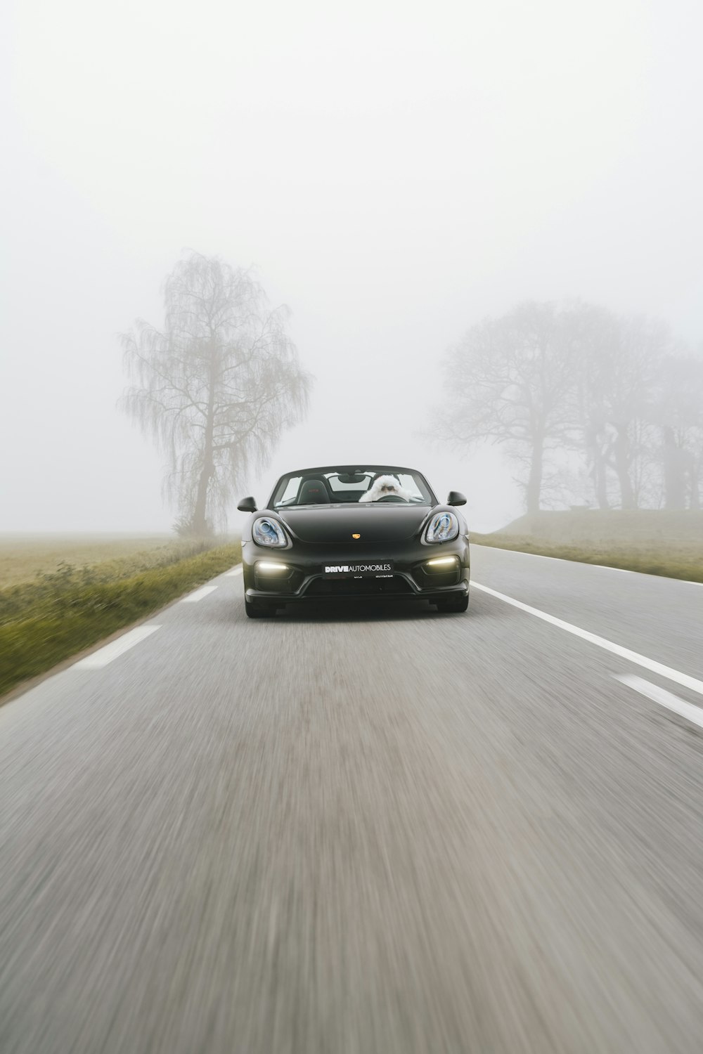 a black sports car driving down a foggy road