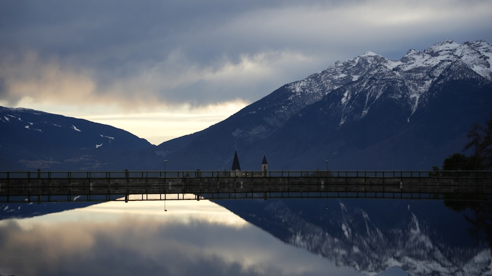 a bridge over a body of water with mountains in the background