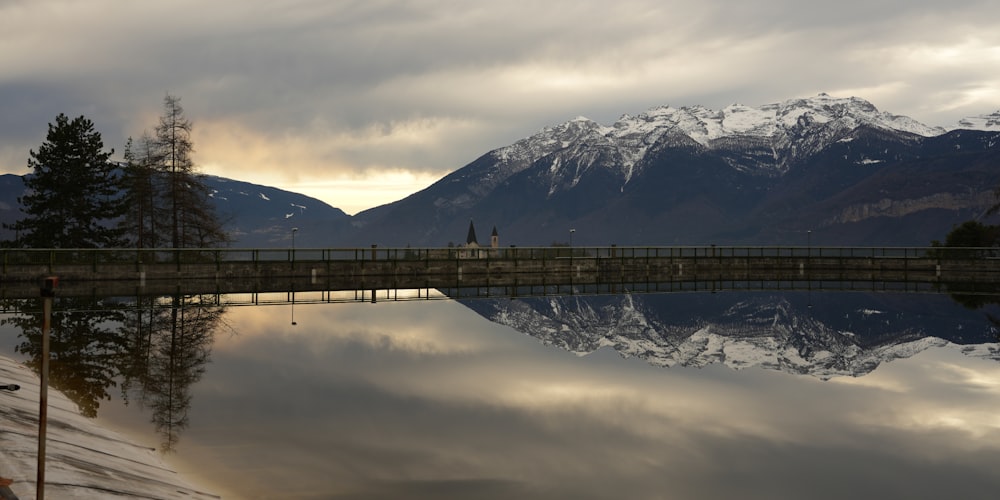 a bridge over a body of water with mountains in the background