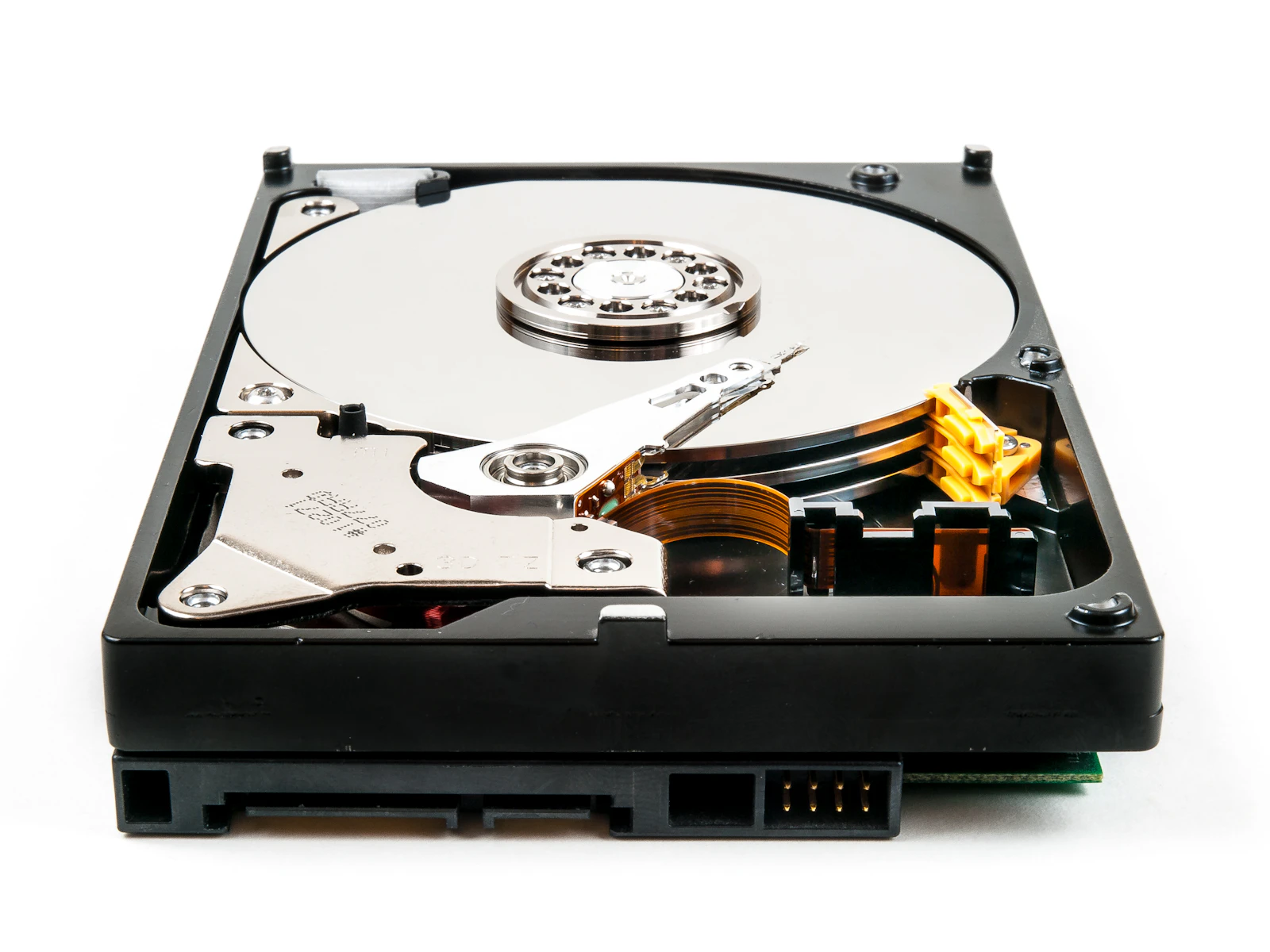 Open 3.5-inch hard disk drive on a white surface showing platters and actuator arm