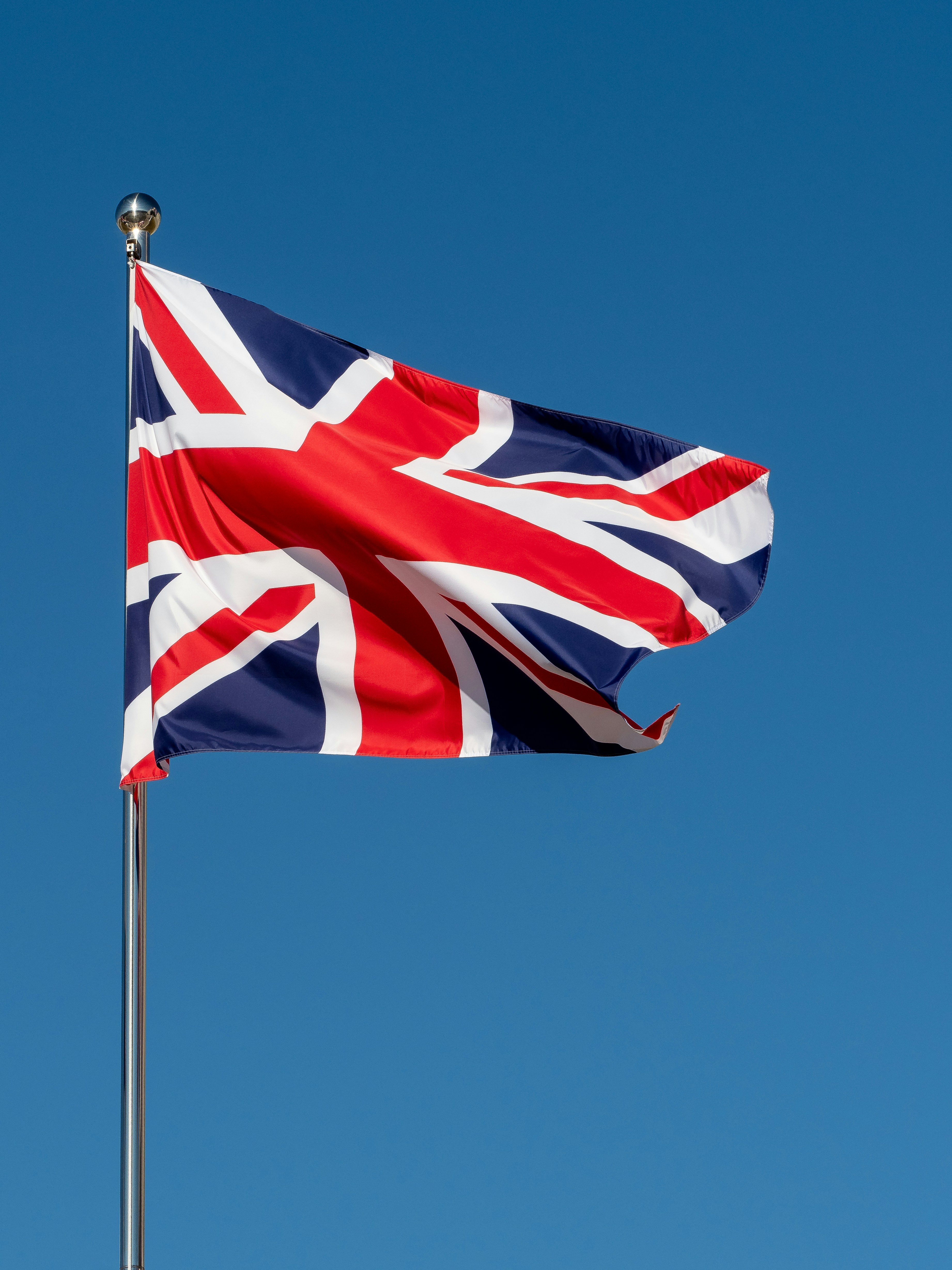 a british flag flying in the blue sky