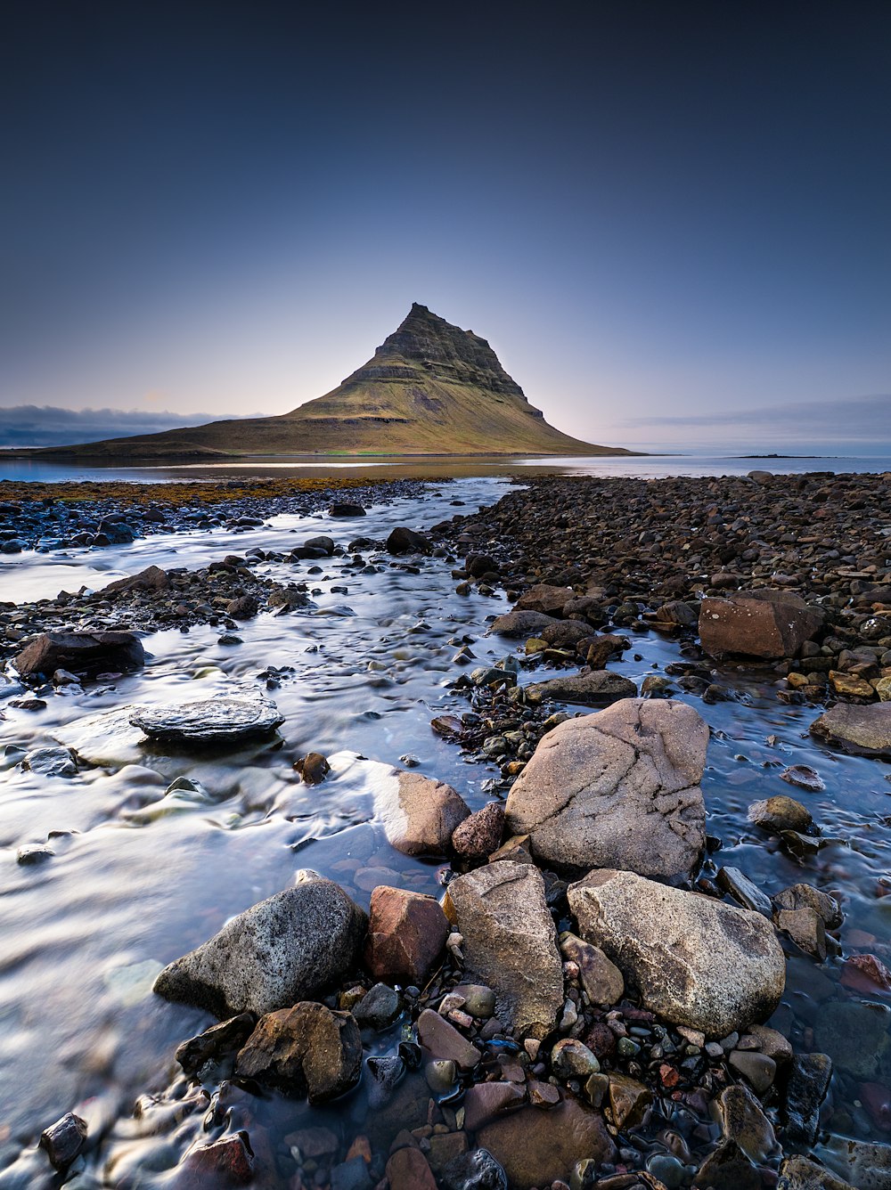 a rocky beach with a mountain in the background