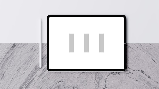 A digital tablet with a blank white screen displaying three vertical grey bars. A white stylus is positioned to the left of the tablet. The background is a textured grey and white surface with a subtle pattern.