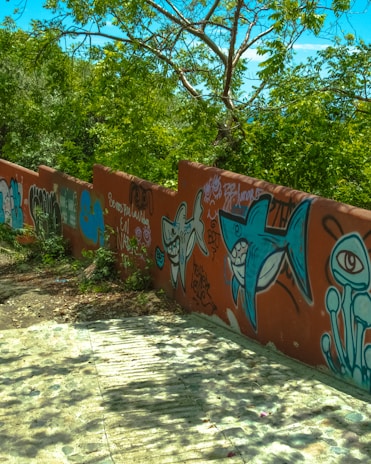 Young artists painting the mural on a sunny day in Cali, surrounded by lush greenery.