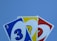 Three playing cards prominently feature the number three in different colors: blue, yellow, and red. These cards are fanned out against a plain background.